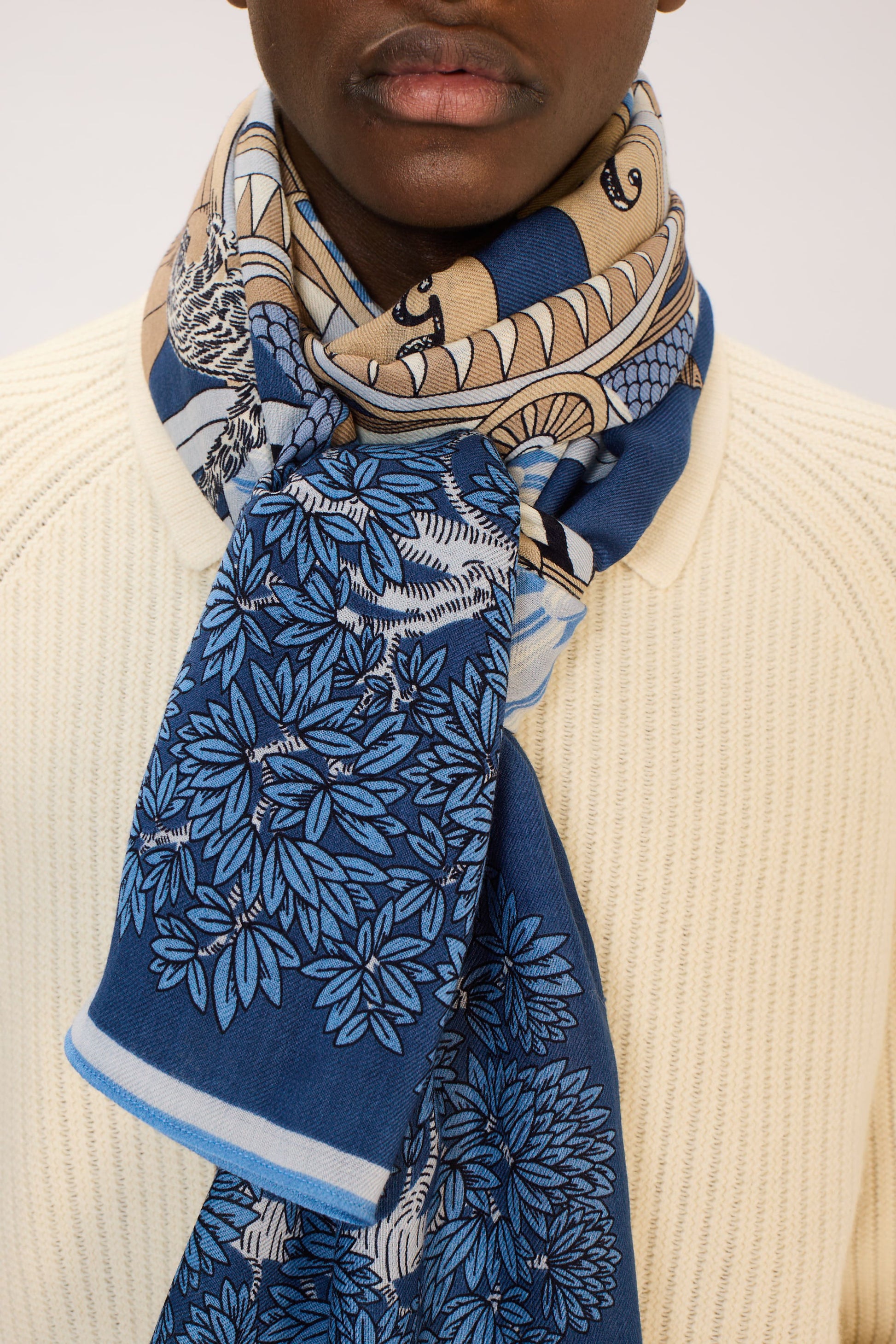 Person wearing a blue patterned scarf with a neutral background