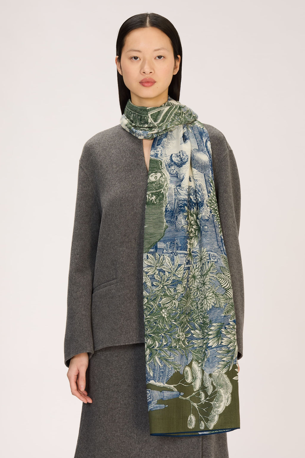 Woman wearing a gray outfit with a long, patterned scarf on a white background