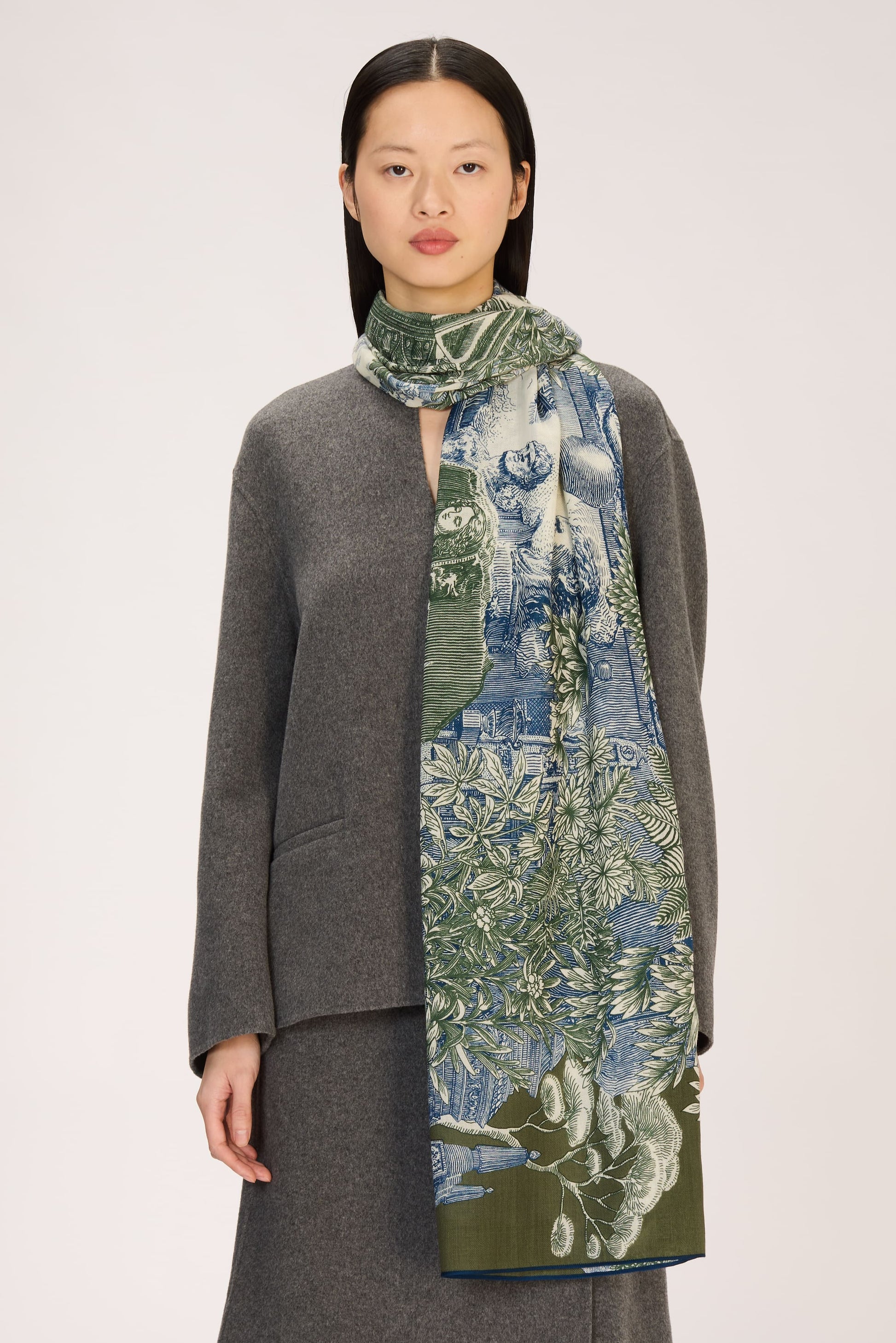 Woman wearing a gray outfit with a long, patterned scarf on a white background