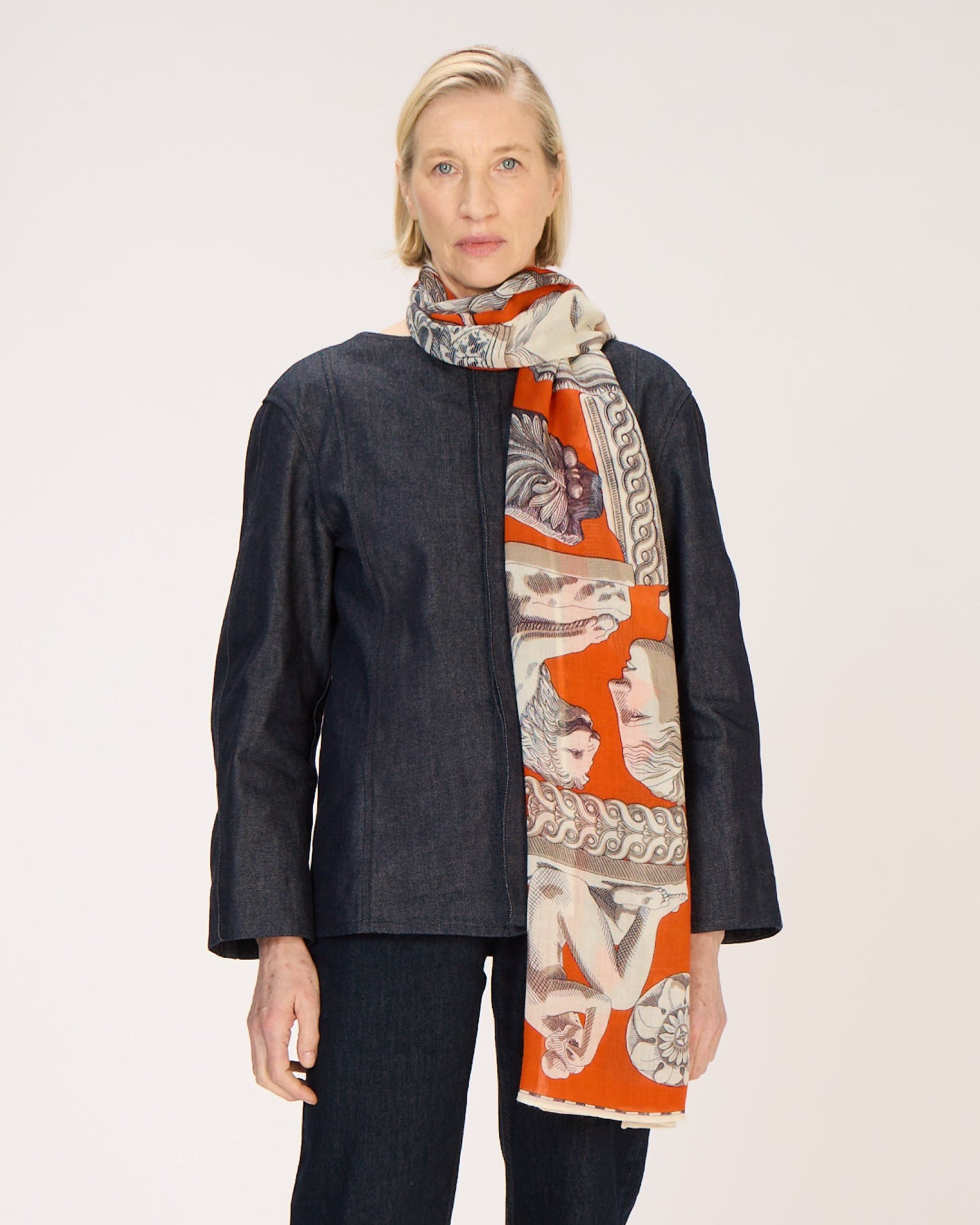 Person wearing a dark coat and patterned scarf on a white background