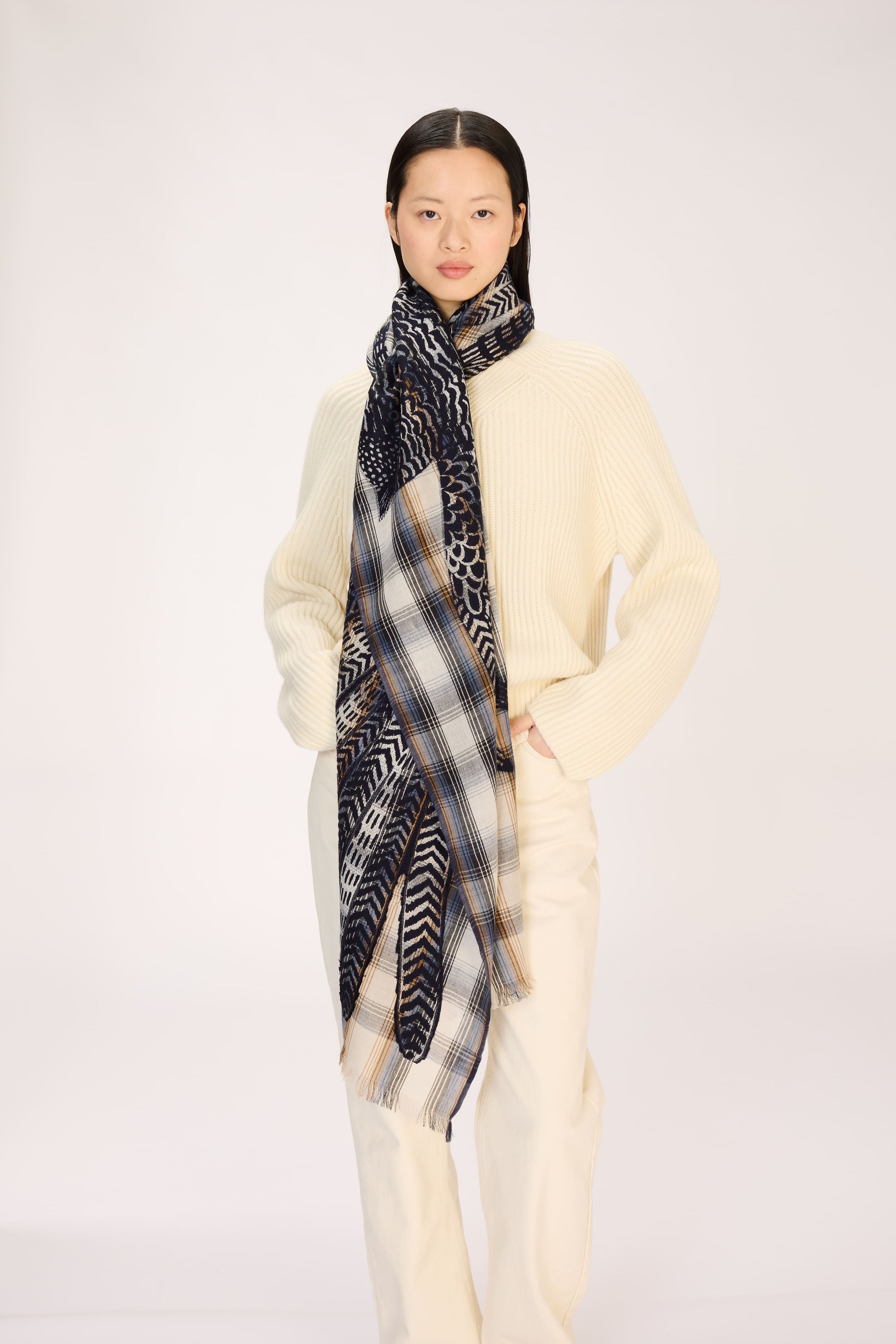 Person wearing a patterned scarf on a plain background
