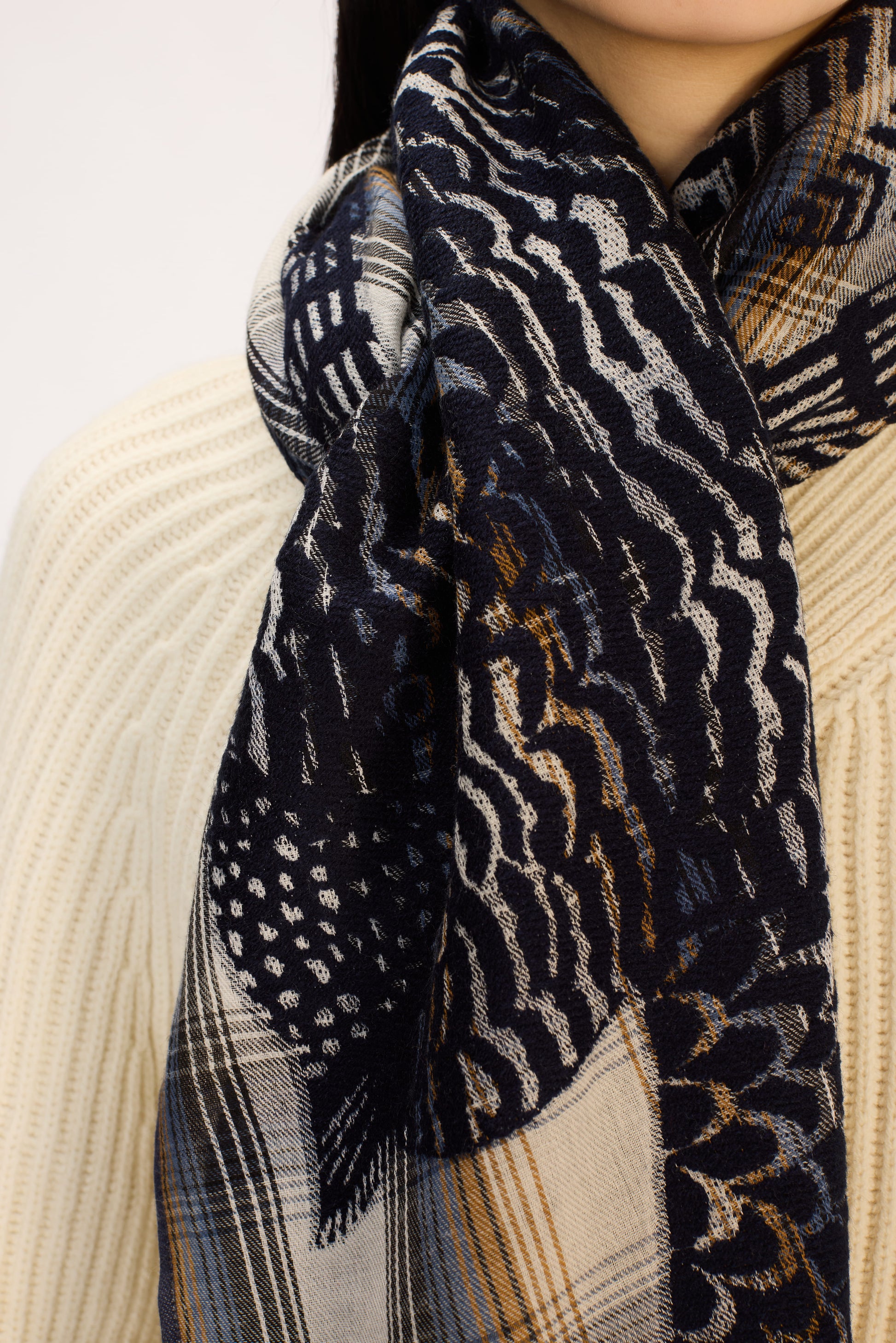Patterned scarf with a mix of designs worn by a person against a neutral background