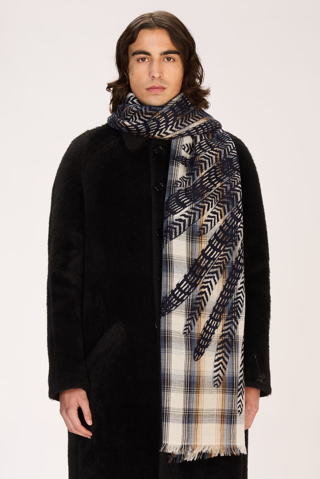 Man wearing a black coat and patterned scarf on a white background