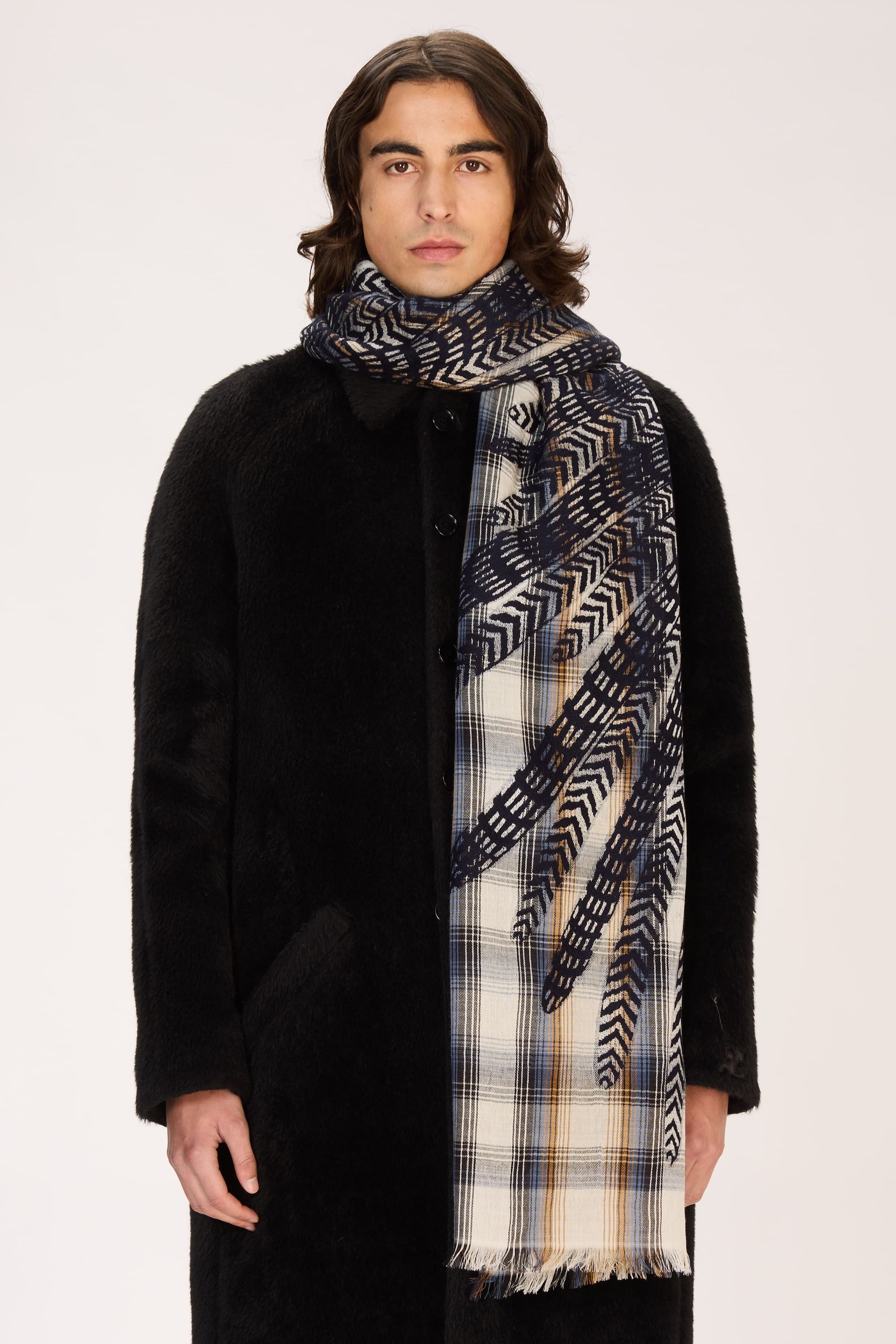 Man wearing a black coat and patterned scarf on a white background