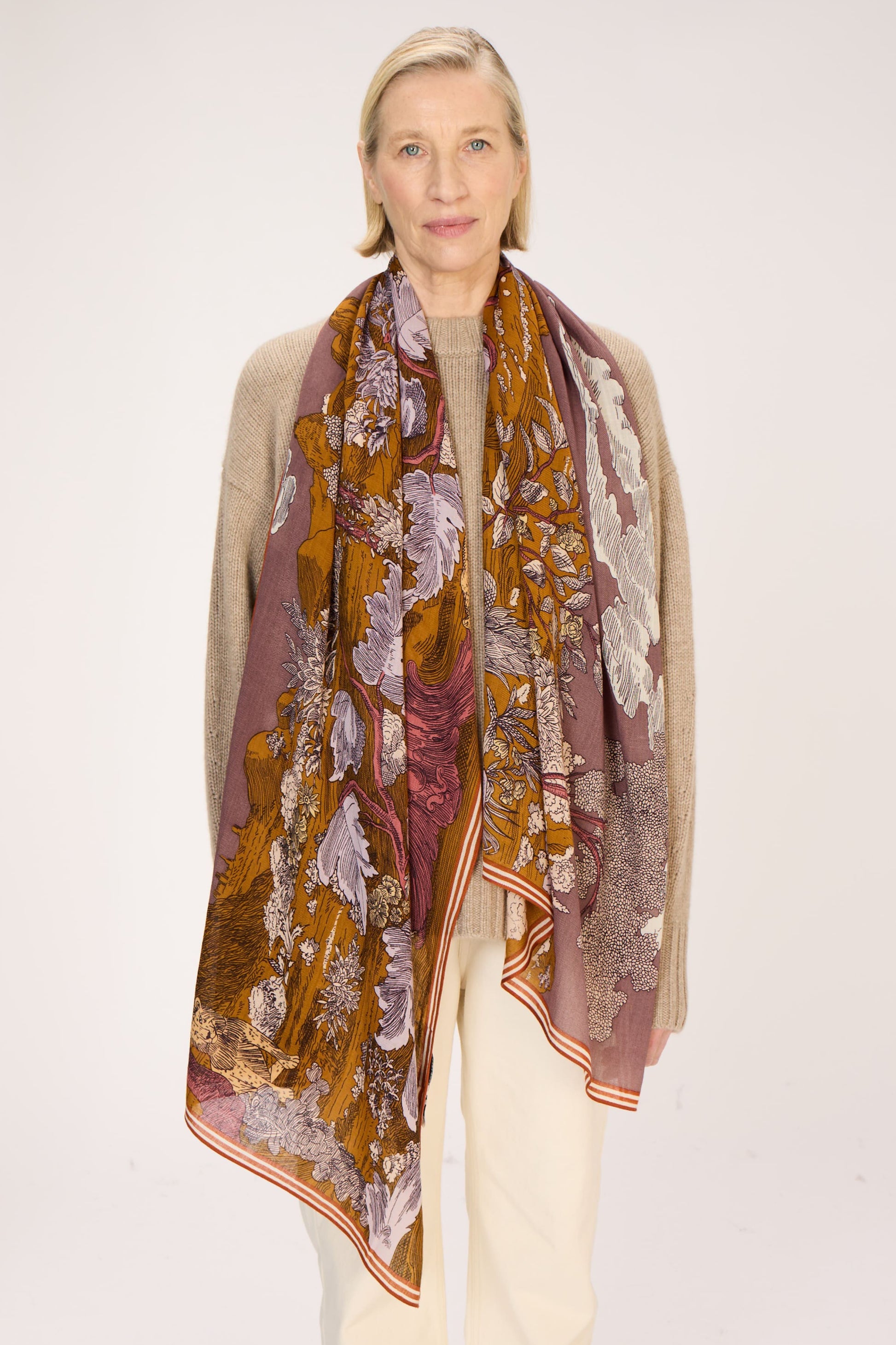 Woman wearing a patterned scarf on a plain background