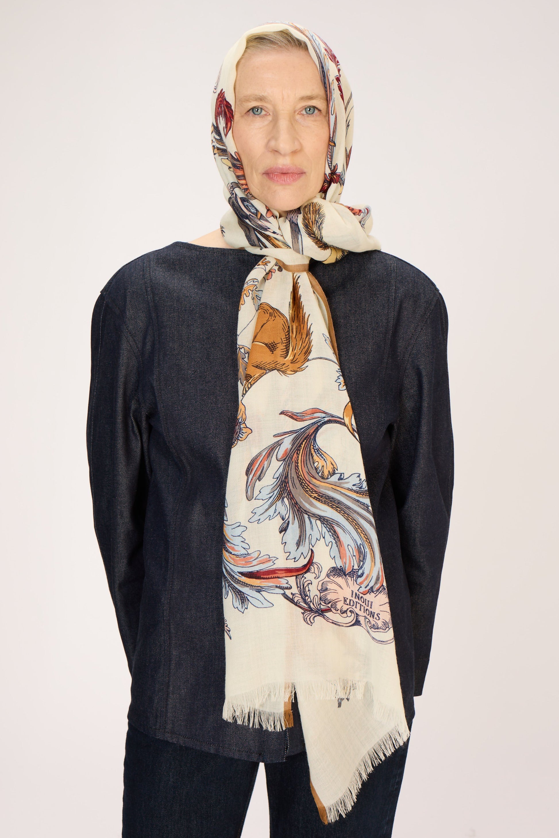 Woman wearing a patterned scarf on a plain background