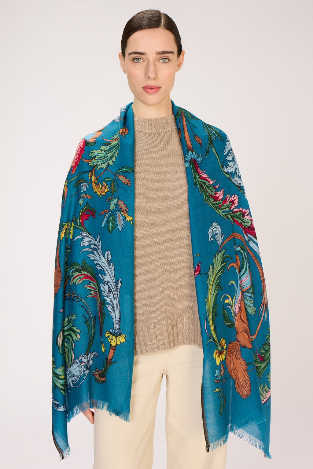 Woman wearing a colorful scarf with a floral and bird pattern on a white background
