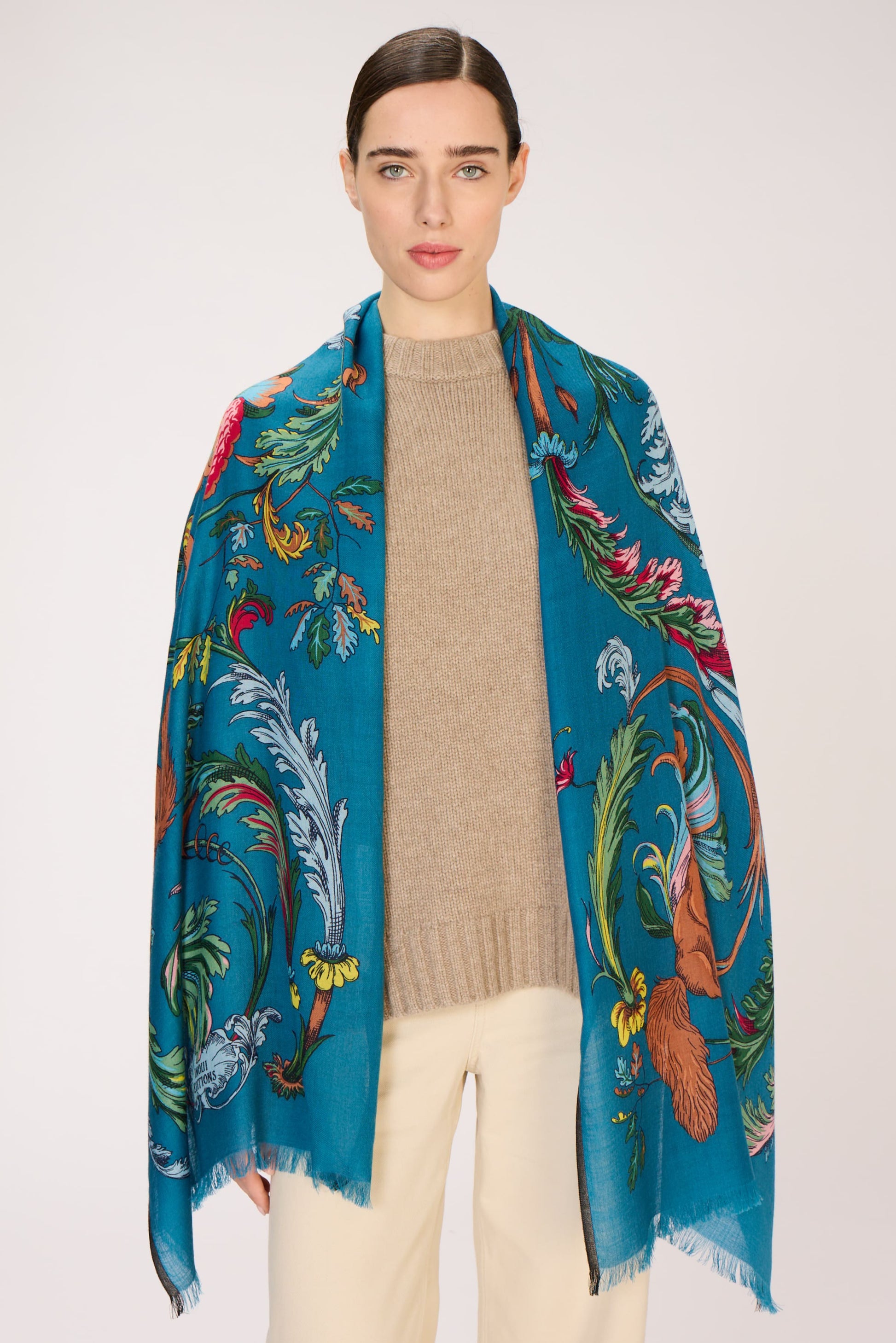 Woman wearing a colorful scarf with a floral and bird pattern on a white background