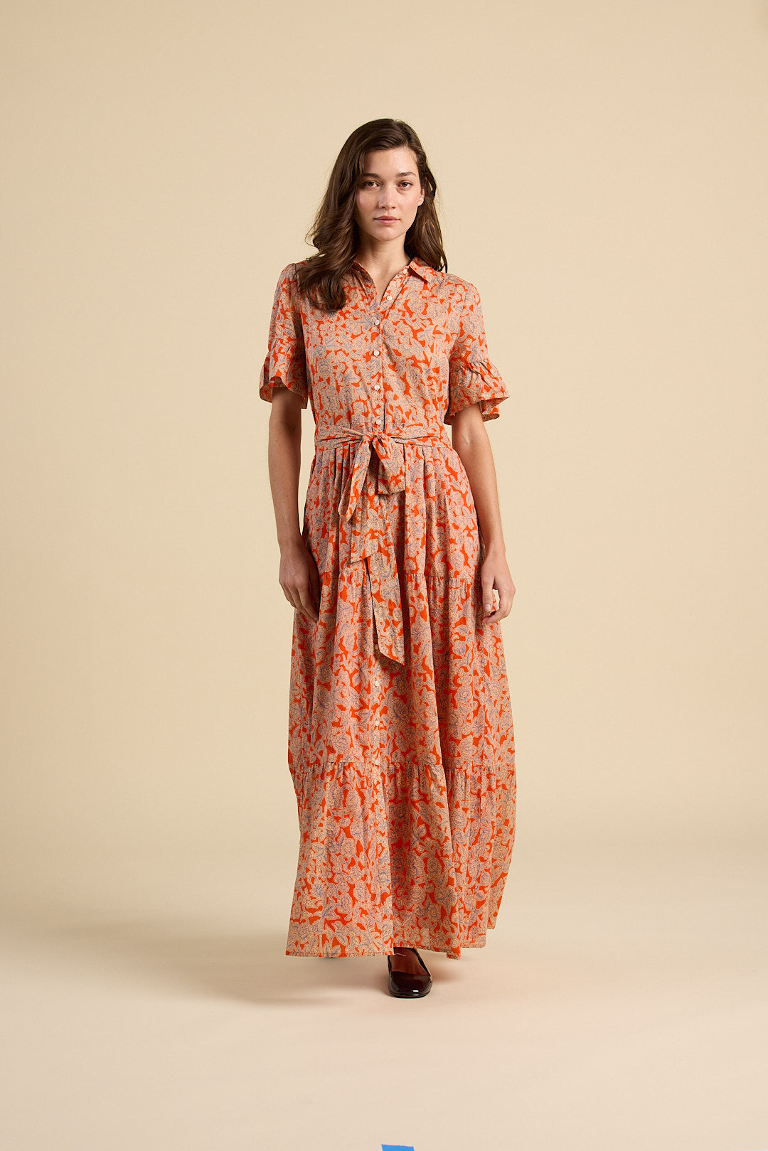 Woman wearing a long floral dress on a beige background