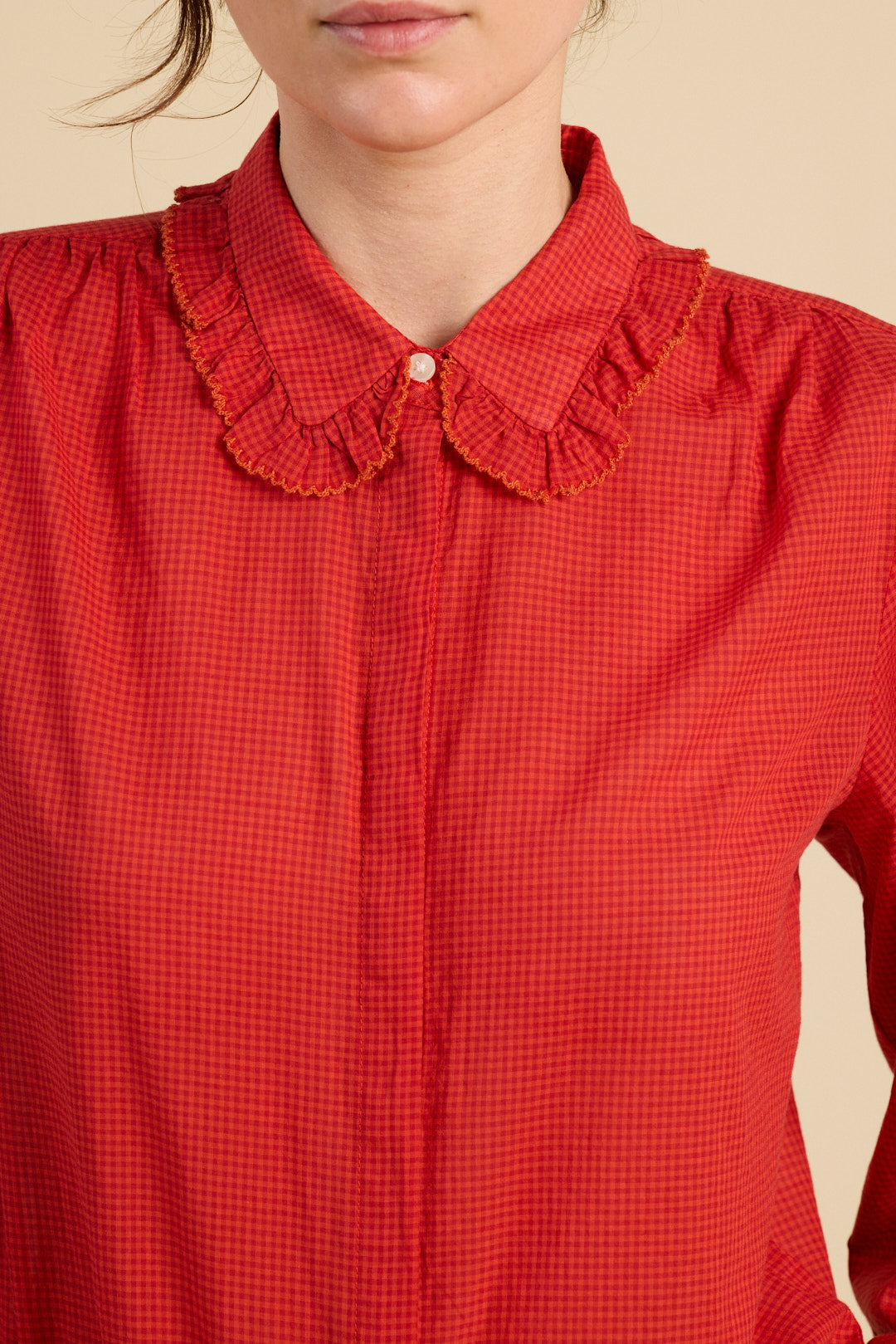 Red checkered blouse with a ruffled collar on a beige background