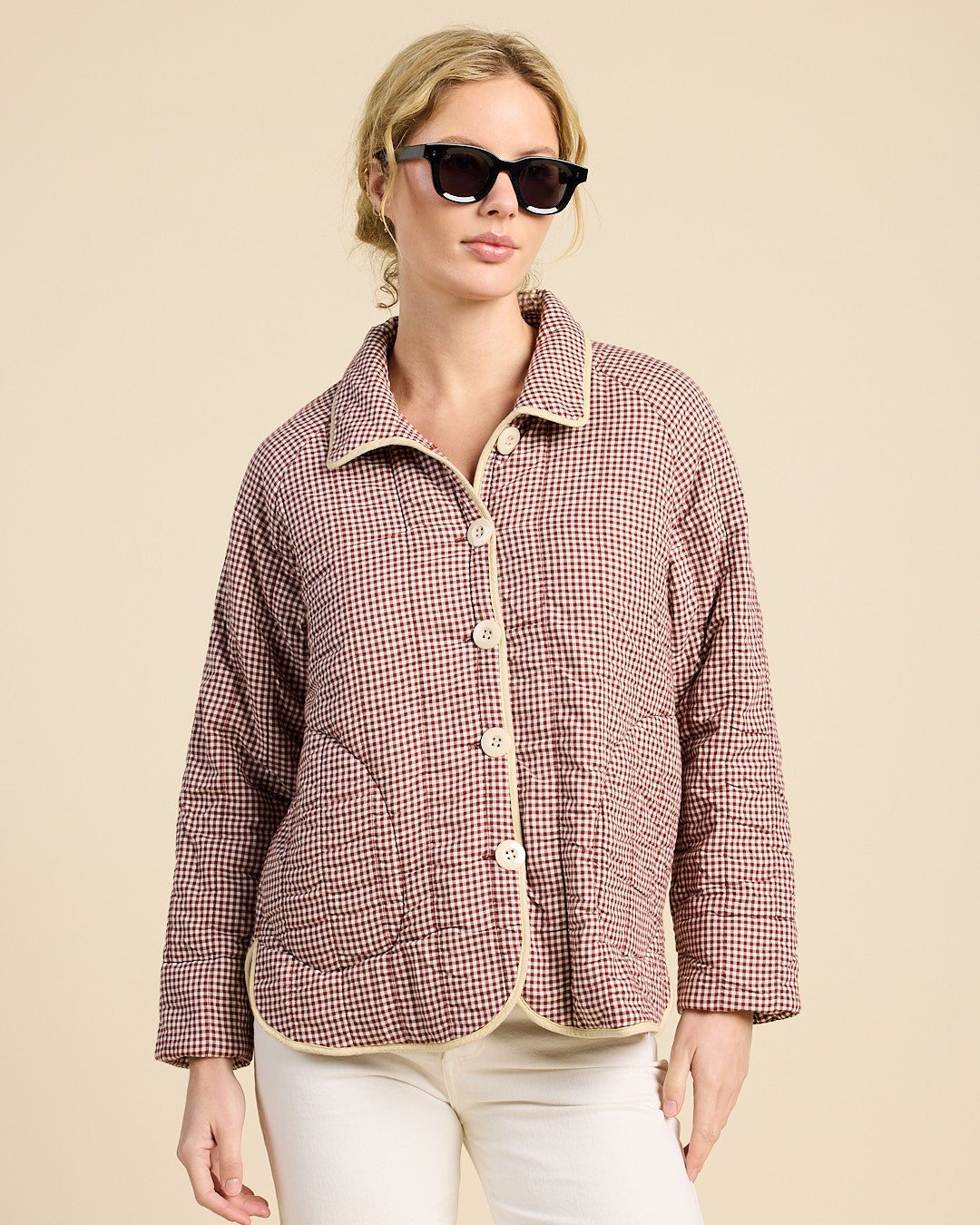 Woman wearing a red and white checkered shirt with a beige collar against a beige background