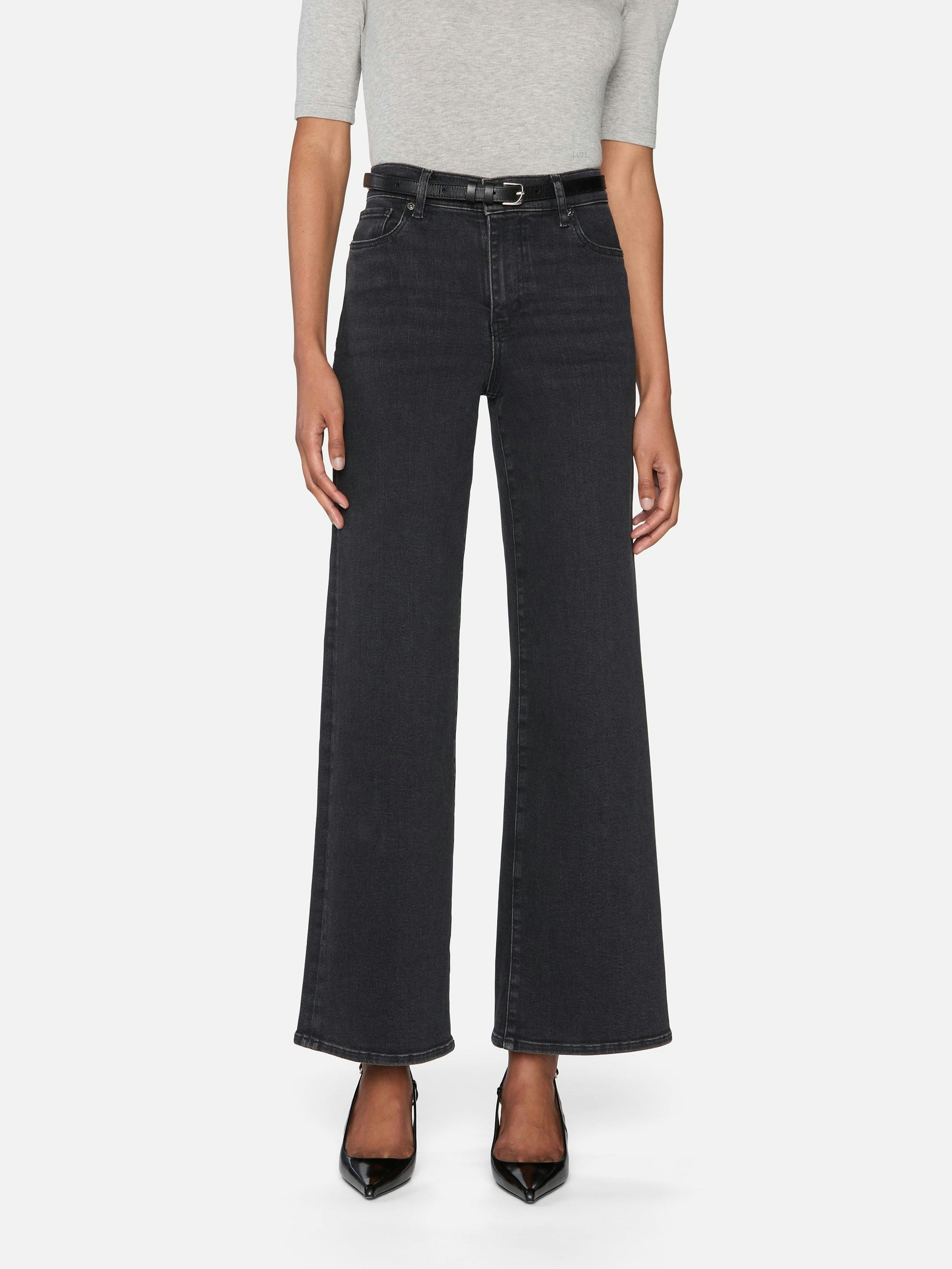 Person wearing black wide-leg jeans on a white background