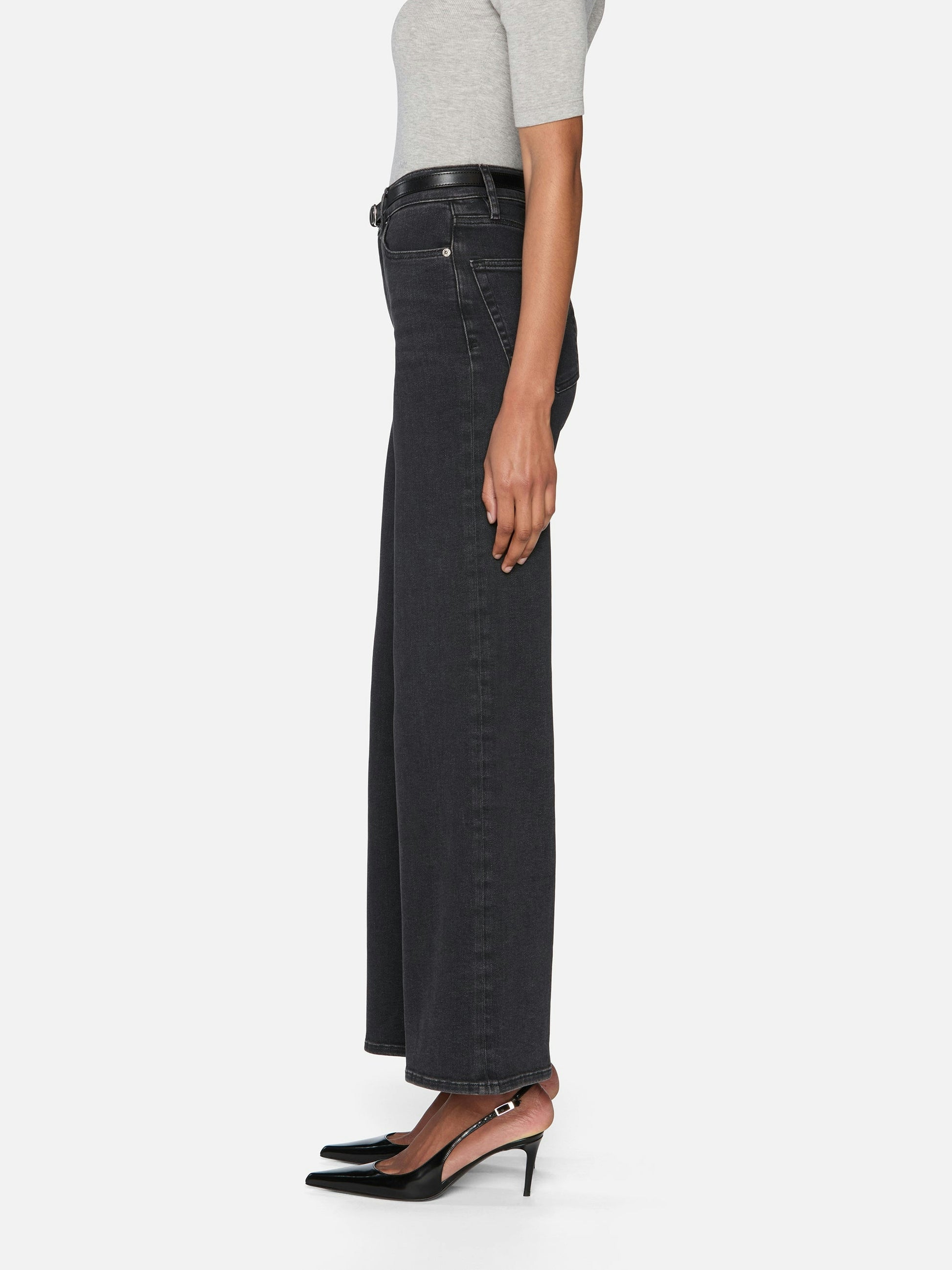 Person wearing black wide-leg jeans on a white background