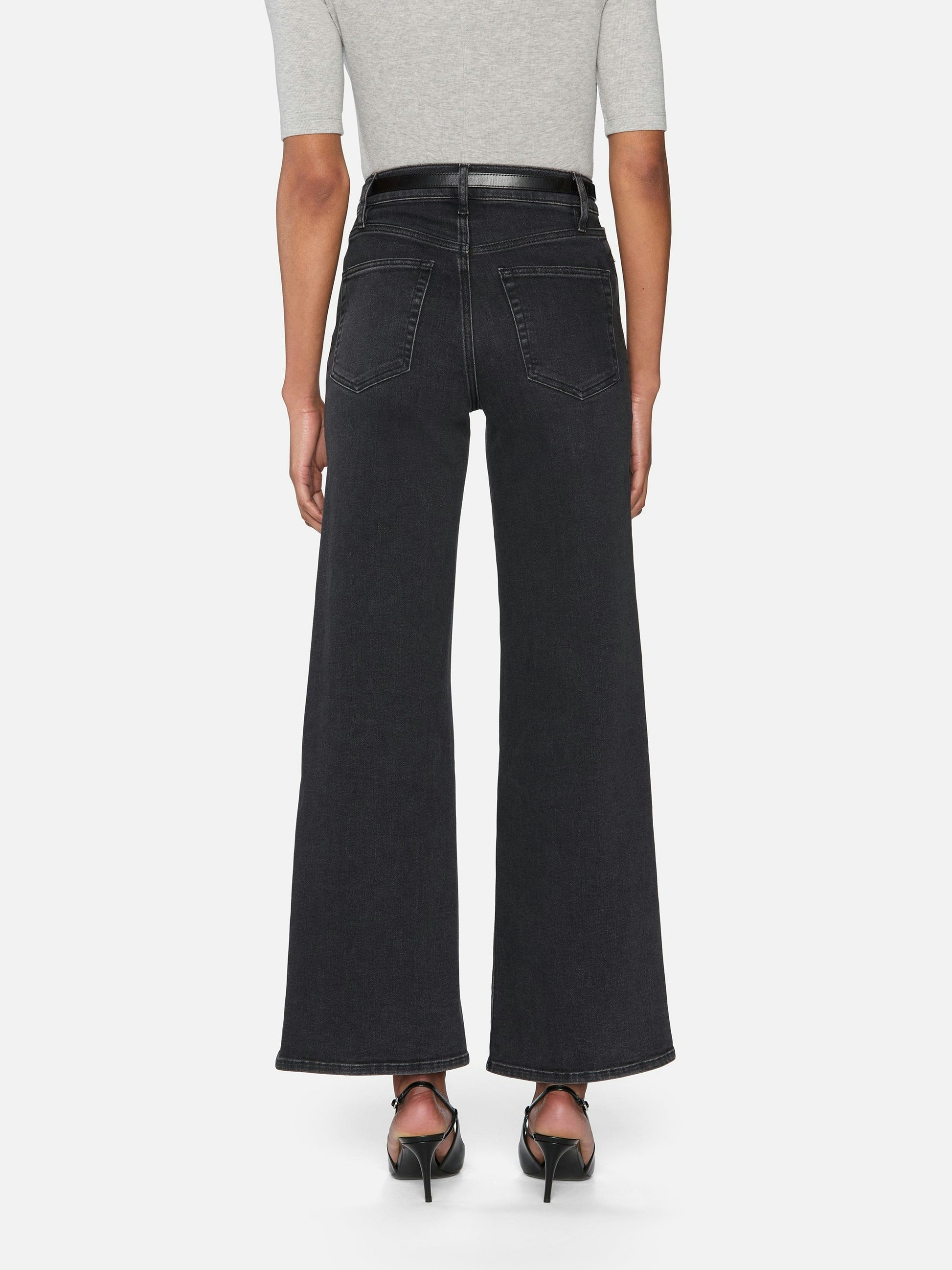 Person wearing black wide-leg jeans on a white background