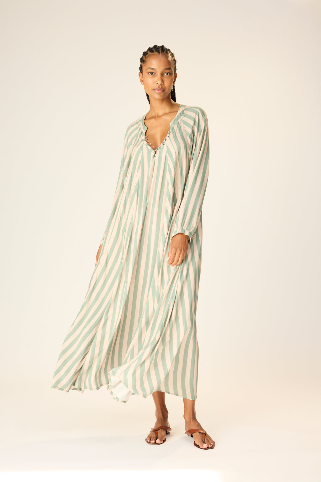 Woman wearing a green and white striped dress on a plain background