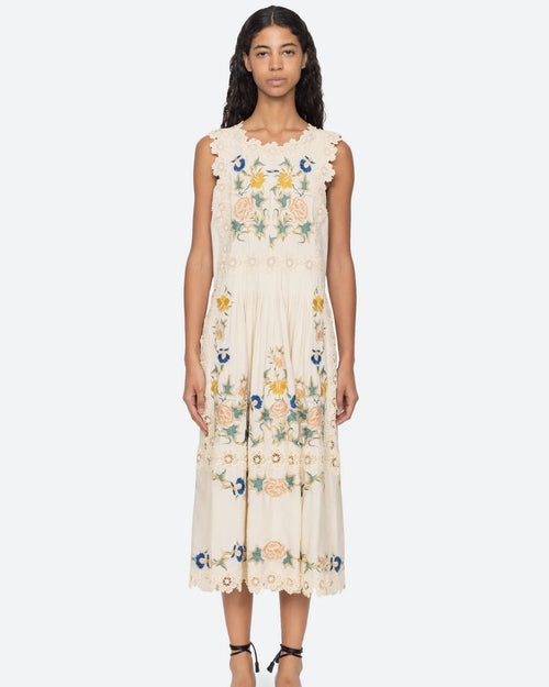 Woman wearing a floral embroidered dress on a white background