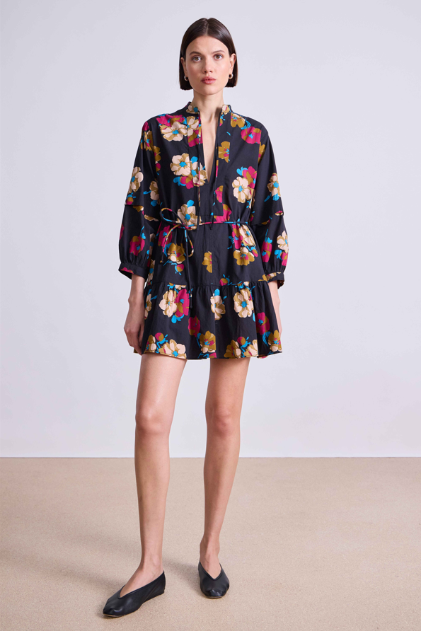 Woman wearing a black floral dress on a plain background