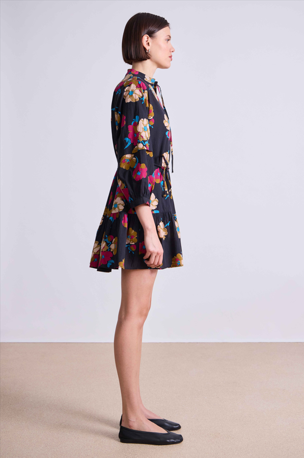 Woman wearing a black floral dress on a plain background