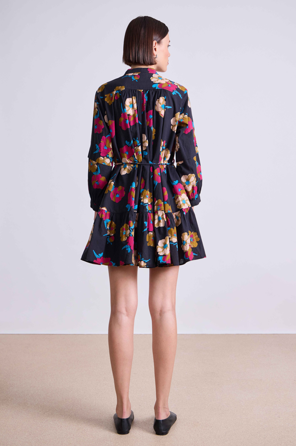 Woman wearing a colorful floral dress with a plain background