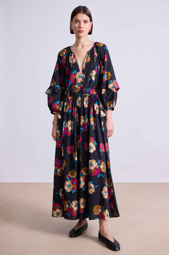 Woman wearing a long floral dress on a plain background