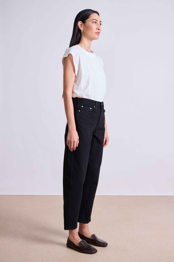 Woman wearing a white top and black pants against a plain background