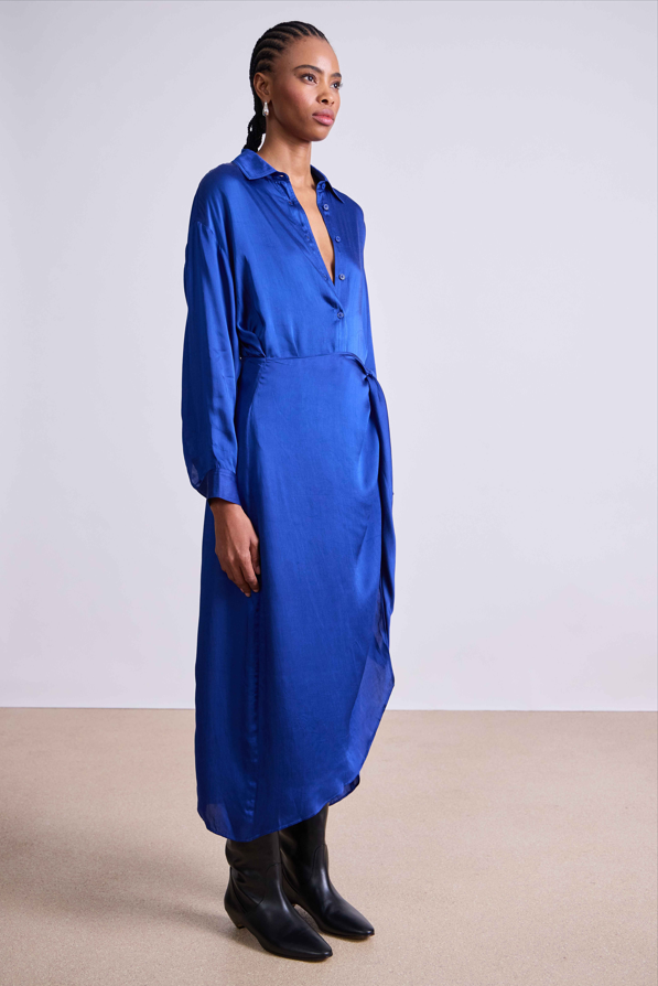 Woman wearing a blue dress standing against a plain background
