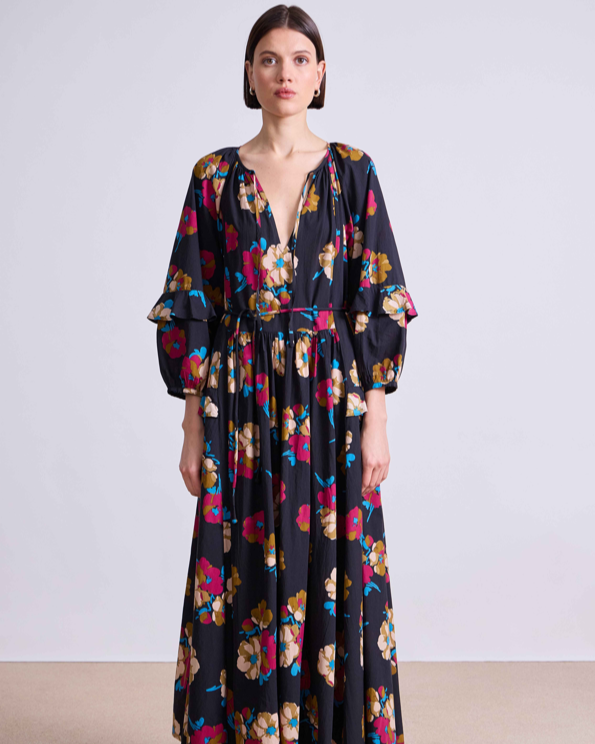 Woman wearing a long floral dress against a plain background