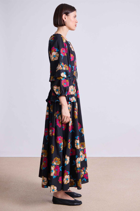 Woman wearing a long floral dress with a plain background