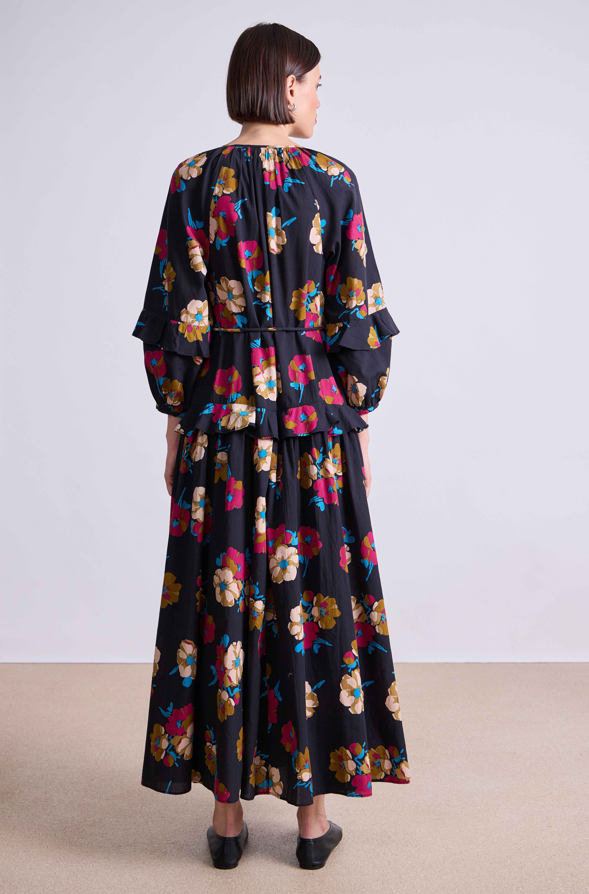 Woman wearing a long floral dress with a plain background