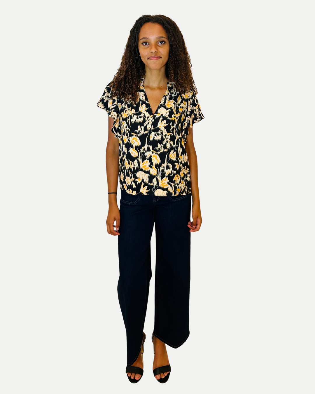 Woman wearing a floral blouse and black pants on a white background