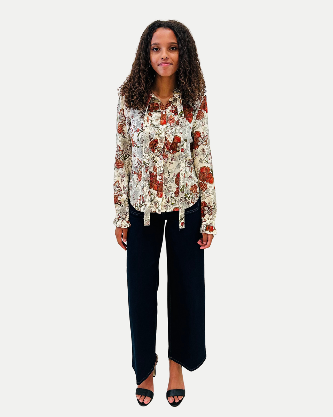 Woman wearing a floral blouse and black pants on a white background