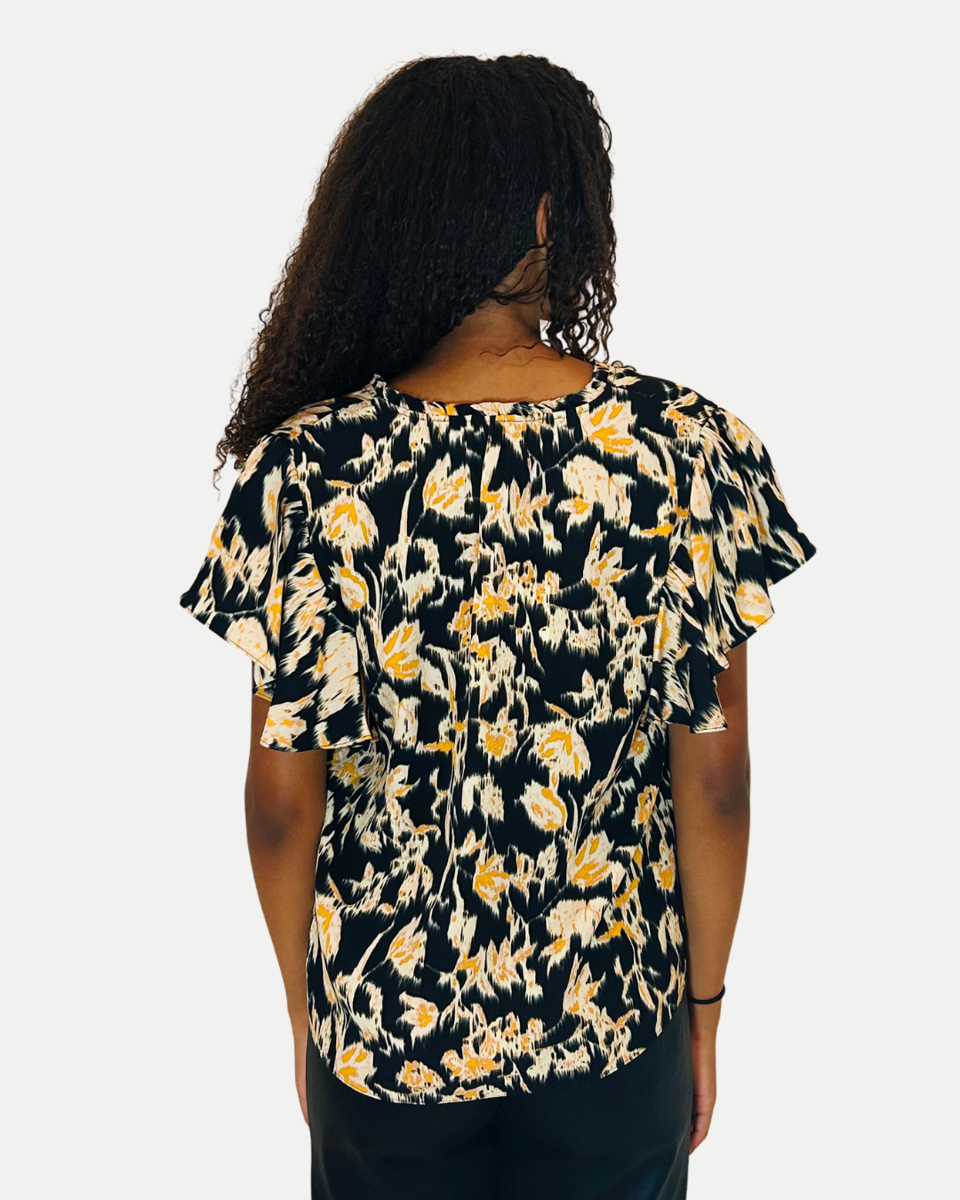Woman wearing a floral blouse with ruffled sleeves on a white background