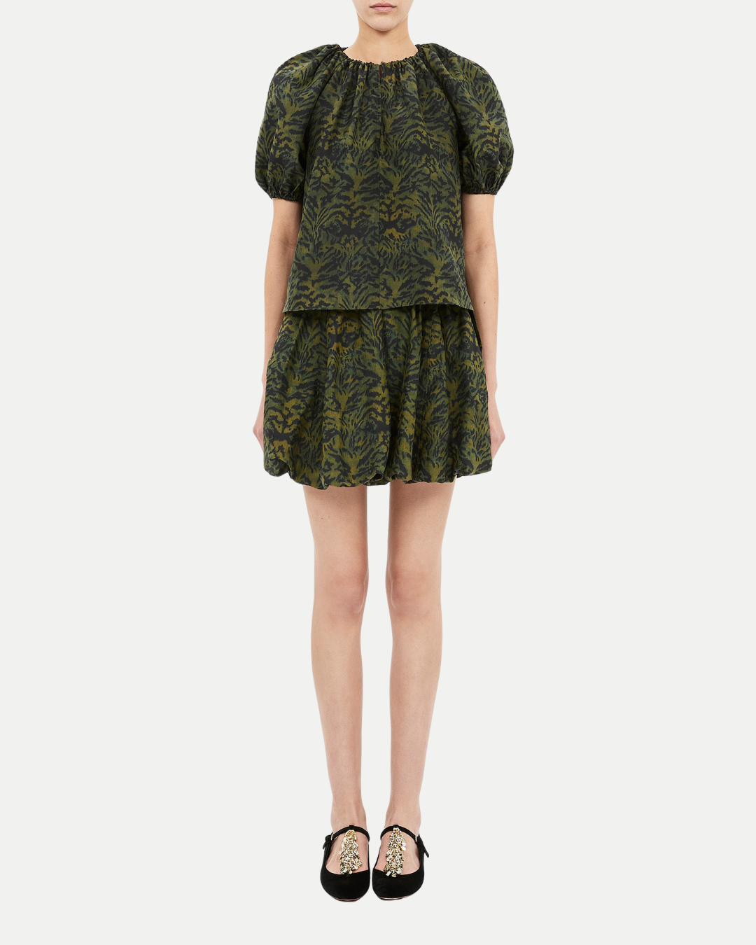 Green patterned dress worn by a person on a white background