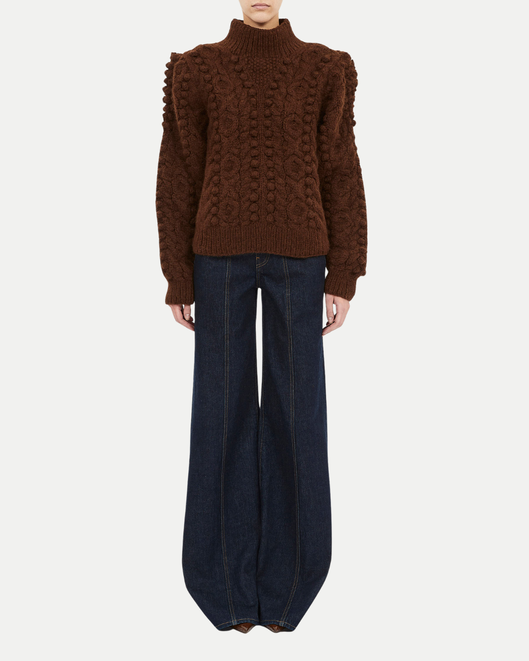 Brown cable knit sweater and dark blue jeans on a white background