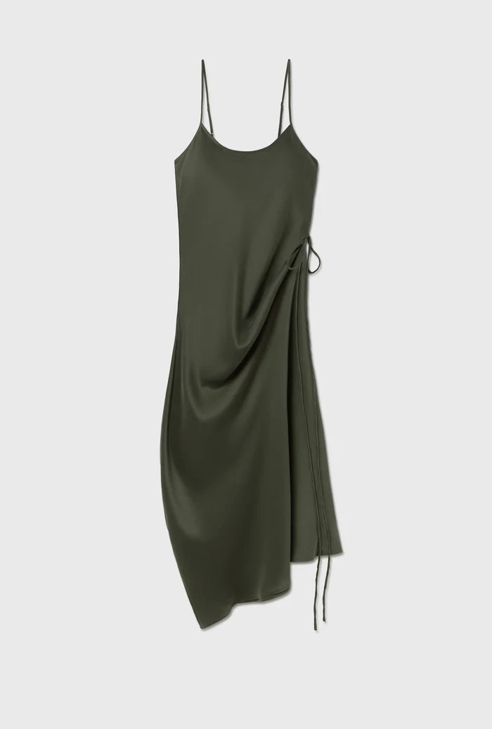 An olive green satin slip dress with thin spaghetti straps, a draped side detail, and a drawstring tie, shown against a light gray background.