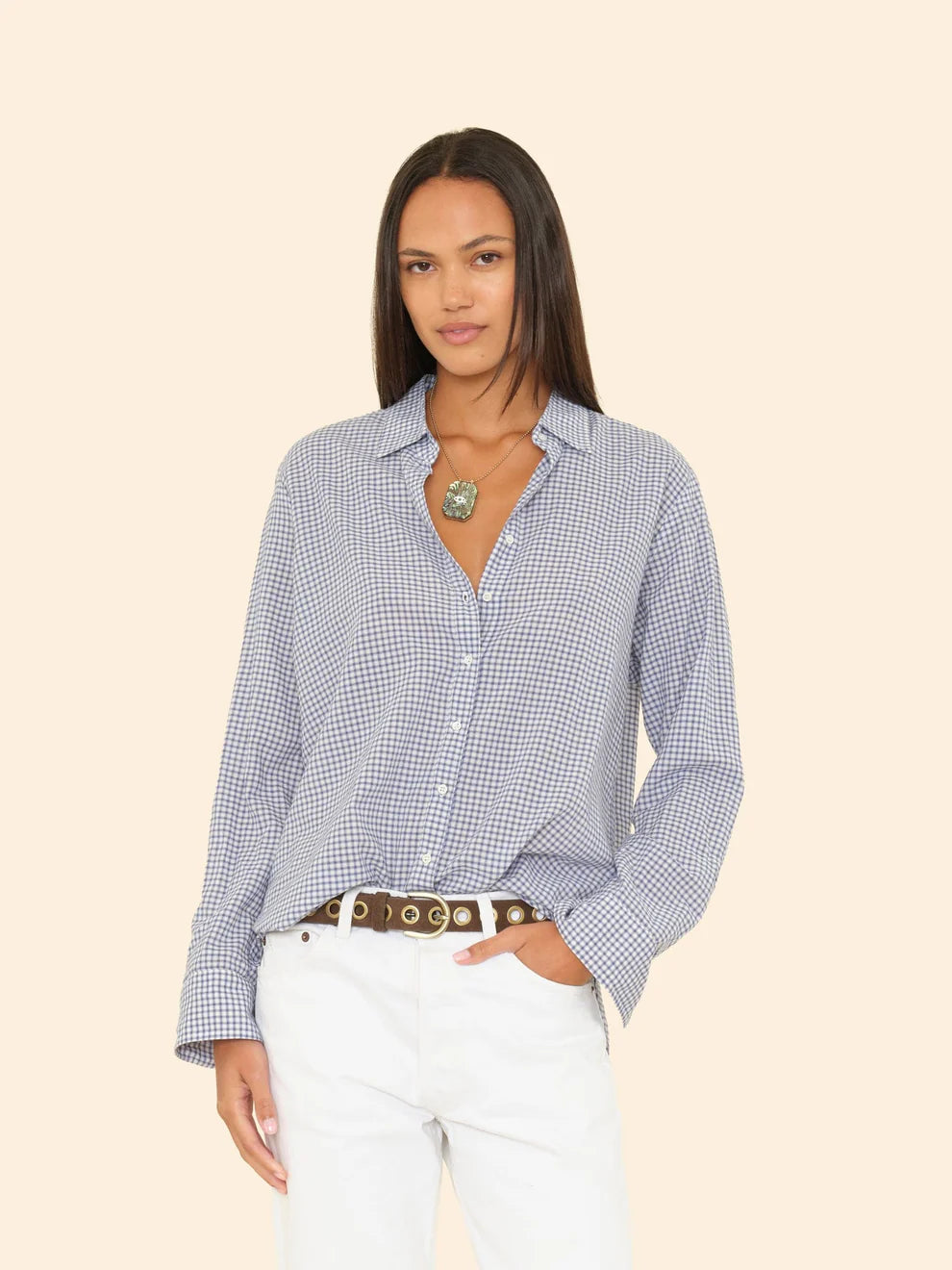 Woman wearing a blue checkered shirt and white pants on a beige background