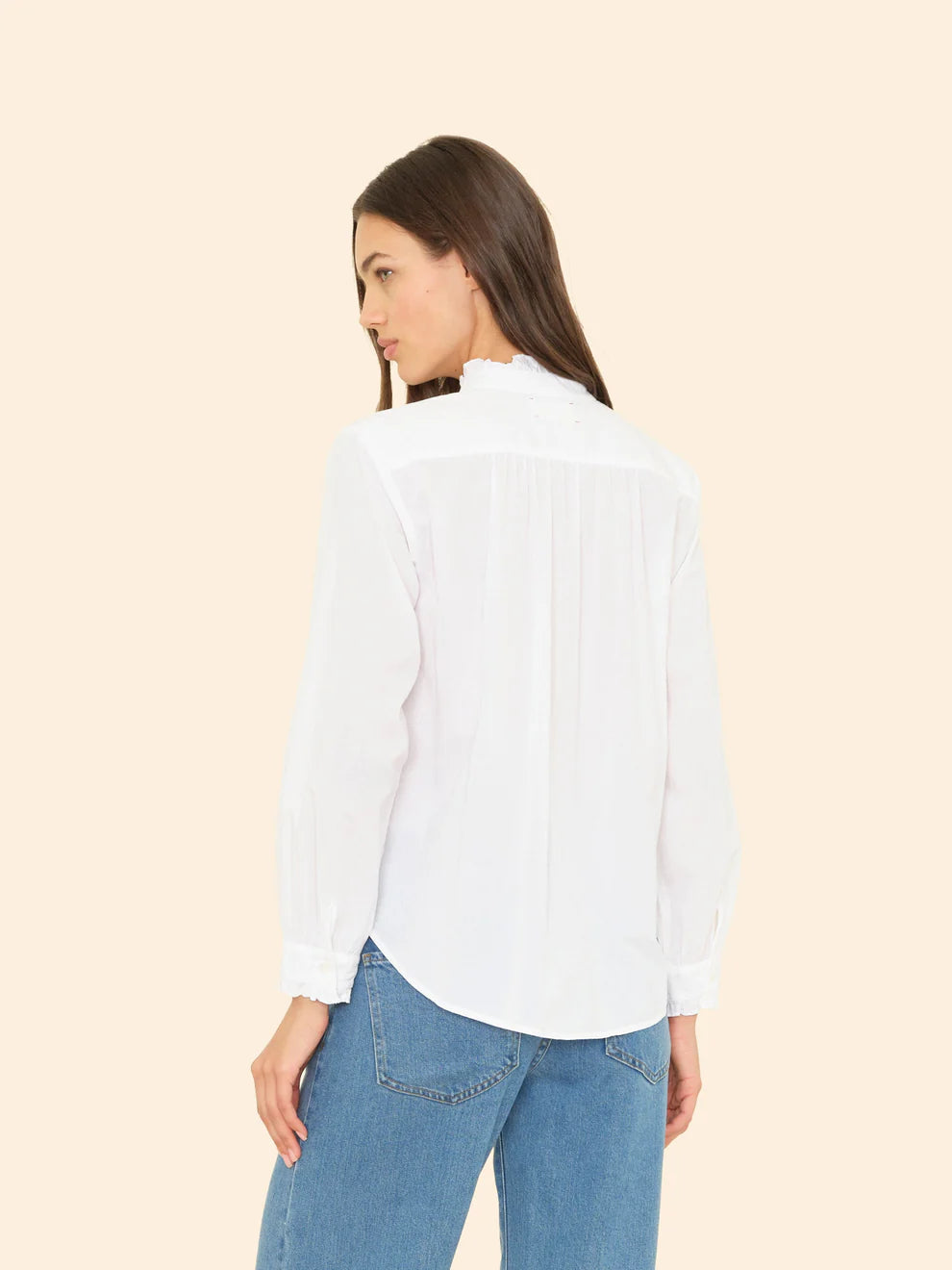 Woman wearing a white shirt and blue jeans on a beige background