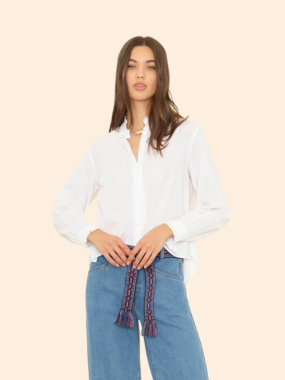 Woman wearing a white blouse and blue jeans with a beige background