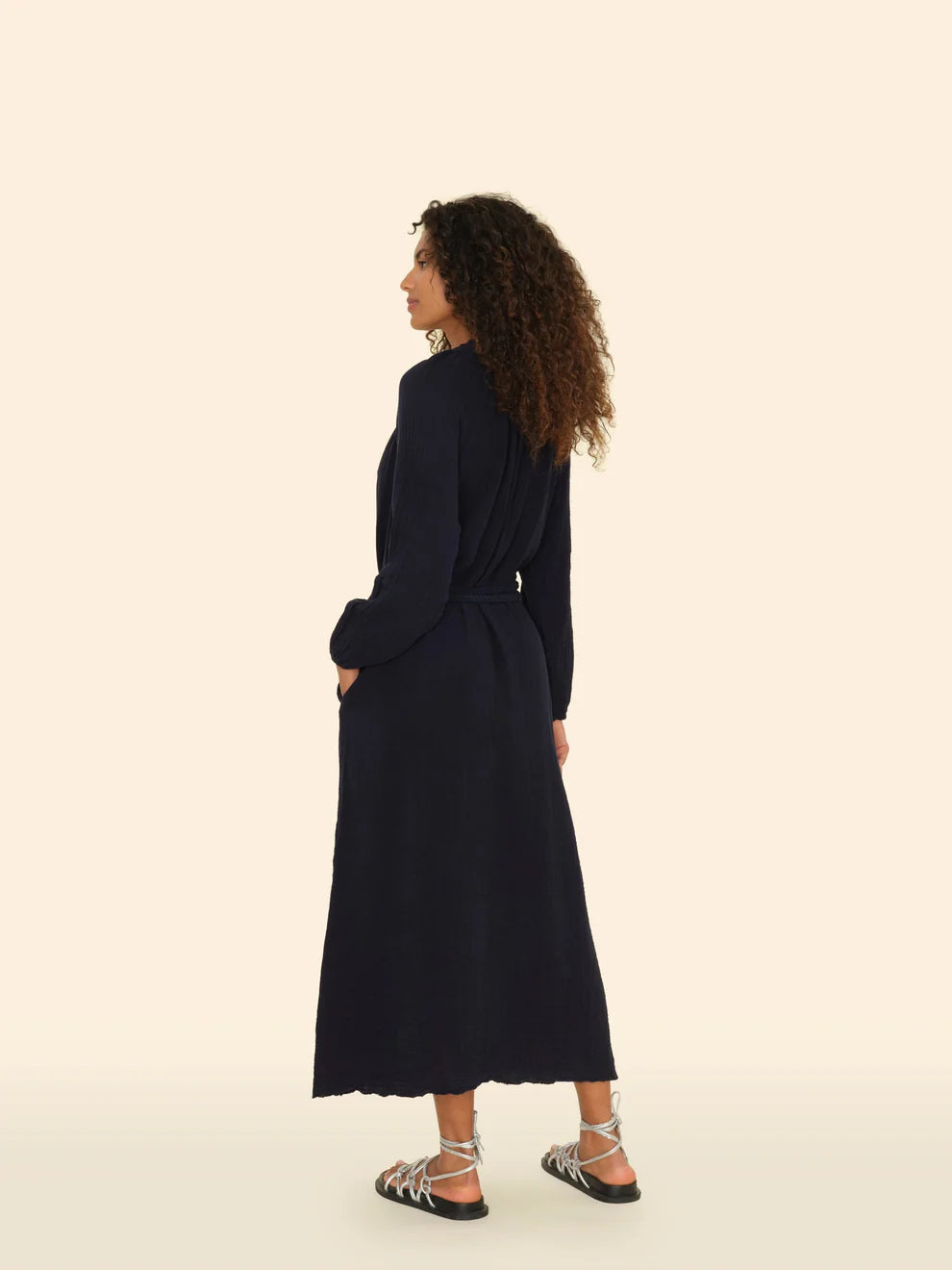 Woman wearing a long navy dress on a beige background